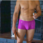 Man wearing purple underwear holding a knife and a can in front of fireplace.