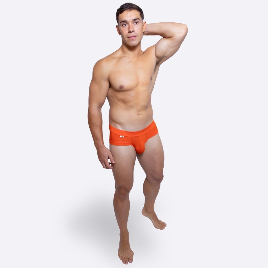 Man wearing bright orange underwear on a white background