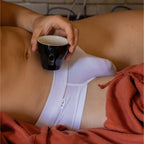 Lifestyle photo of white briefs with person holding a cup